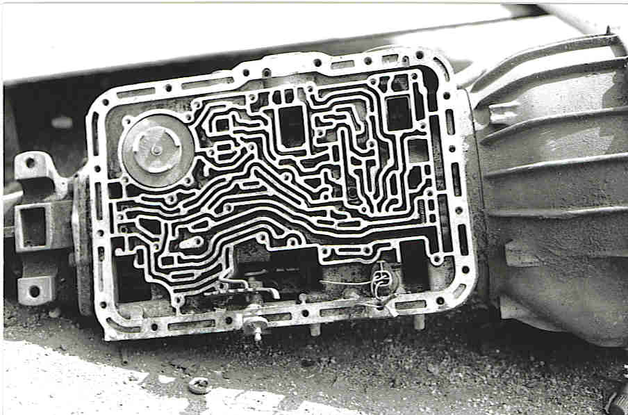The exposed underside of an automatic transmission, its oil passages forming an intricate maze-like pattern